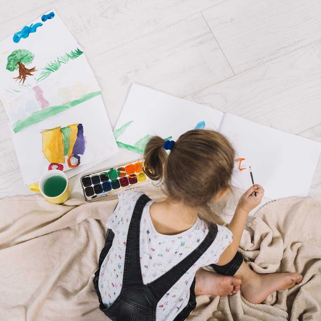 Criança colorindo com tinta aquarela no chão