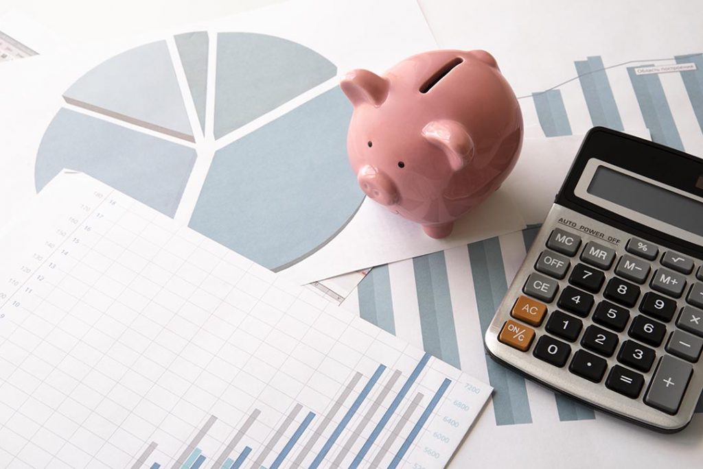 mesa com gráficos calculadora e cofrinho de moedas