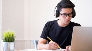 Homem de camiseta preta com fones de ouvido segurando um lápis