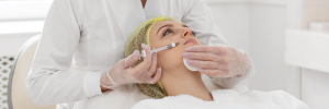 Profissional esteticista aplicando na pele do rosto de uma cliente uma seringa, realizando um tratamento estético.