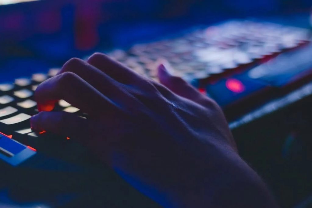 uma mão tocando o teclado do computador iluminado por led