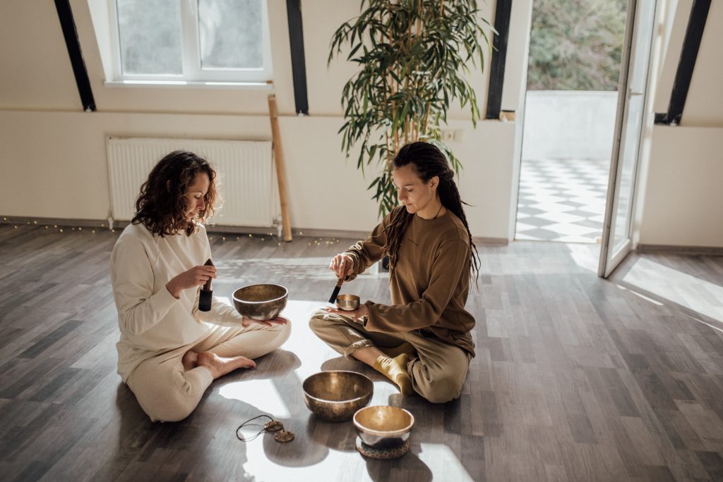Duas mulheres sentadas ao chão praticando musicoterapia