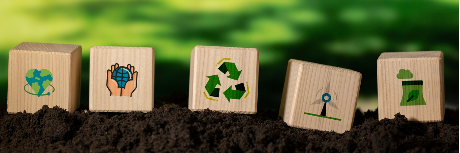 Figuras de blocos de madeira estampados com símbolos de reciclagem e outros referentes à educação ambiental em fundo verde.