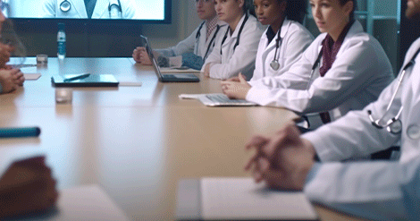 Profissionais da saúde em jalecos brancos discutem assuntos importantes em uma mesa de conferência