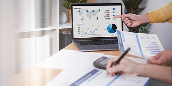 Pessoa analisando gráficos e dados de tráfego global em um laptop, discutindo resultados de marketing digital