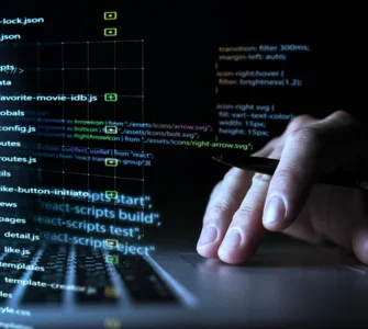 Imagem de uma mão interagindo com um teclado de laptop, com códigos e pastas de programação projetados sobre a tela.