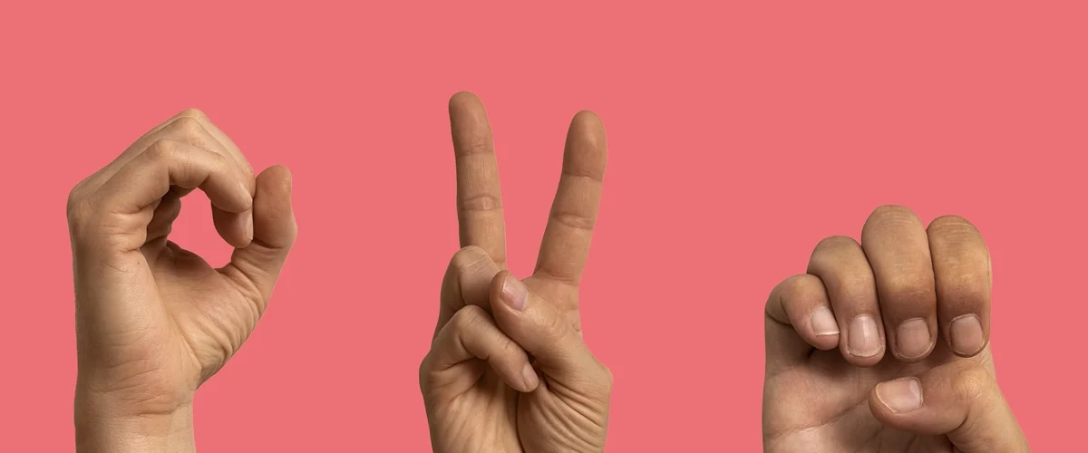 Imagem mostrando três mãos fazendo gestos em Libras (Língua Brasileira de Sinais) com um fundo rosa.