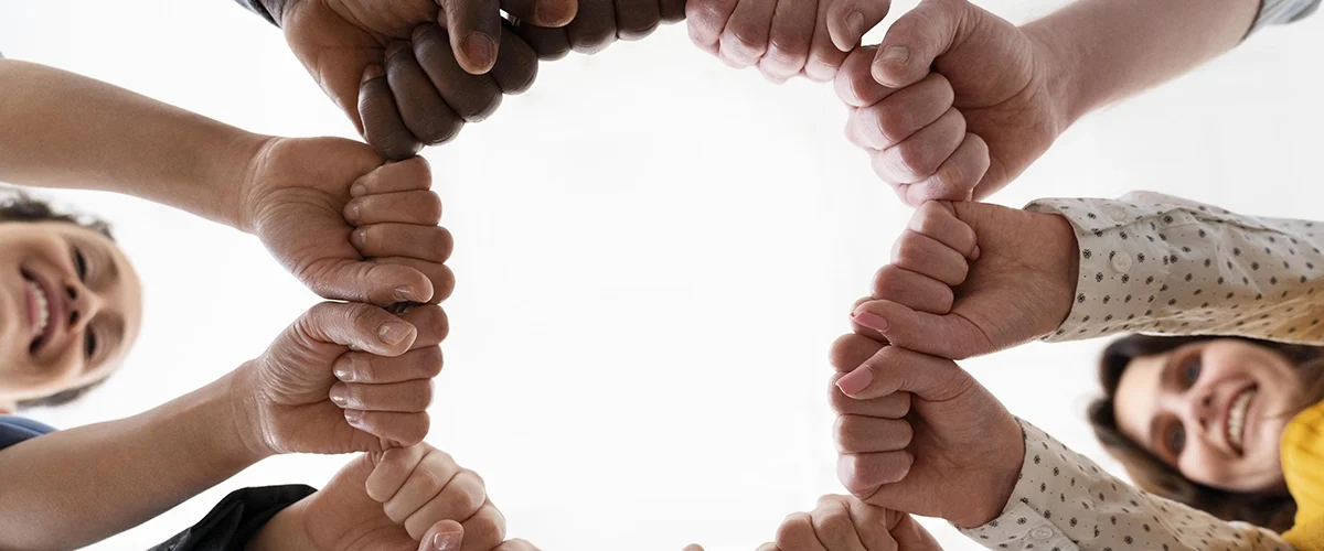 Imagem de mãos diversas unidas em um círculo, simbolizando igualdade e direitos humanos.
