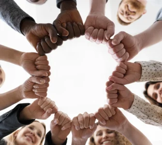 Imagem de mãos diversas unidas em um círculo, simbolizando igualdade e direitos humanos.