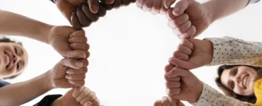 Imagem de mãos diversas unidas em um círculo, simbolizando igualdade e direitos humanos.