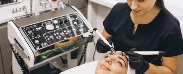 Profissional biomédico esteticista realizando tratamento facial com equipamentos modernos em uma clínica estética.