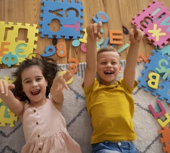 Crianças sorrindo e brincando com peças de encaixe coloridas em formato de letras, estimulando o aprendizado lúdico.
