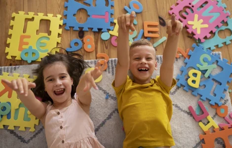Crianças sorrindo e brincando com peças de encaixe coloridas em formato de letras, estimulando o aprendizado lúdico.