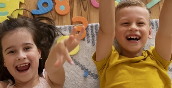 Crianças sorrindo e brincando com peças de encaixe coloridas em formato de letras, estimulando o aprendizado lúdico.