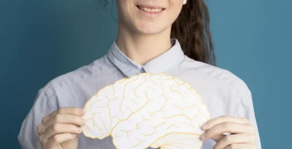 Mulher segurando uma ilustração de um cérebro amarelo, sorrindo, em frente a um fundo azul.