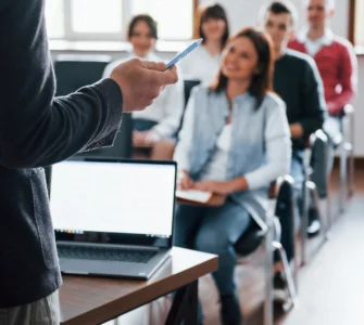 Professor conduzindo aula com uso de metodologias ativas de aprendizagem a grupo de alunos jovens em sala de aula.