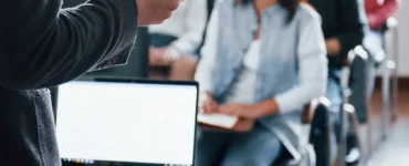 Professor conduzindo aula com uso de metodologias ativas de aprendizagem a grupo de alunos jovens em sala de aula.
