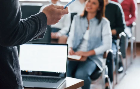 Professor conduzindo aula com uso de metodologias ativas de aprendizagem a grupo de alunos jovens em sala de aula.
