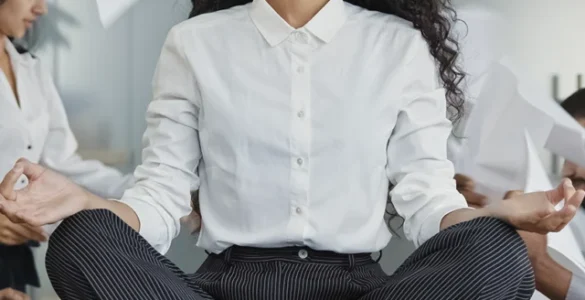 Mulher meditando sobre a mesa em meio ao caos no escritório, simbolizando calma no estresse do trabalho.