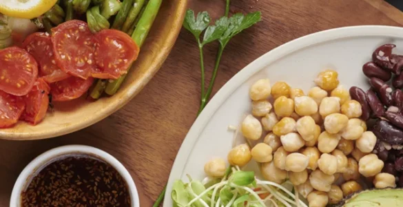 Prato colorido com legumes grelhados, grãos, sementes, castanhas e vegetais frescos em fundo escuro.