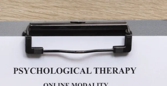 Mesa com teclado, óculos, caneta e ficha de terapia psicológica online com anotações de sessões anteriores.
