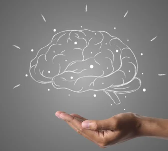 Mão sustentando um cérebro desenhado com conexões, simbolizando inteligência ou neuromarketing.