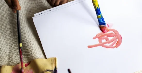 Crianças e adultos pintando com tintas coloridas sobre papel, rodeados por materiais de arte diversos.
