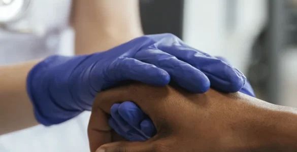 Profissional de saúde segurando a mão de um paciente, demonstrando cuidado e empatia no atendimento.