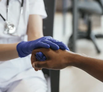 Profissional de saúde segurando a mão de um paciente, demonstrando cuidado e empatia no atendimento.
