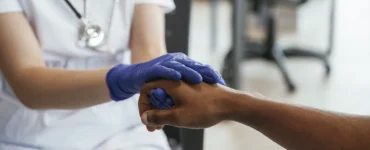Profissional de saúde segurando a mão de um paciente, demonstrando cuidado e empatia no atendimento.