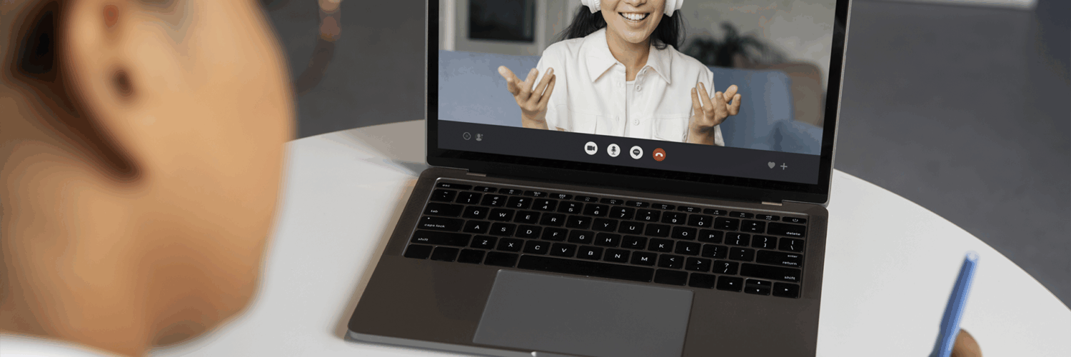 Pessoa assiste a uma videochamada em notebook enquanto faz anotações em um caderno com caneta azul.