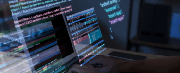 Pessoa programando em notebook com códigos em JavaScript e React projetados na tela em ambiente escuro.