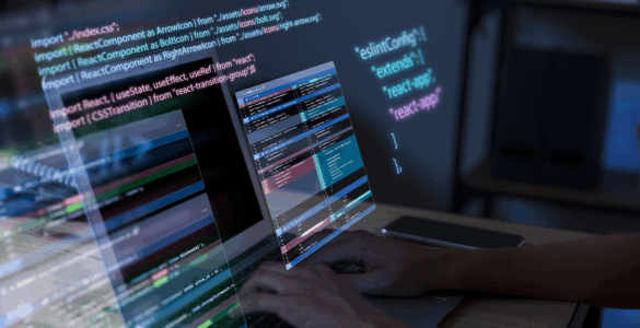 Pessoa programando em notebook com códigos em JavaScript e React projetados na tela em ambiente escuro.