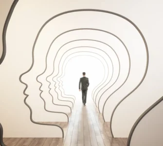 Homem caminha por passagens em formato de perfis humanos, simbolizando autoconhecimento e desenvolvimento pessoal.