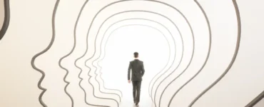 Homem caminha por passagens em formato de perfis humanos, simbolizando autoconhecimento e desenvolvimento pessoal.