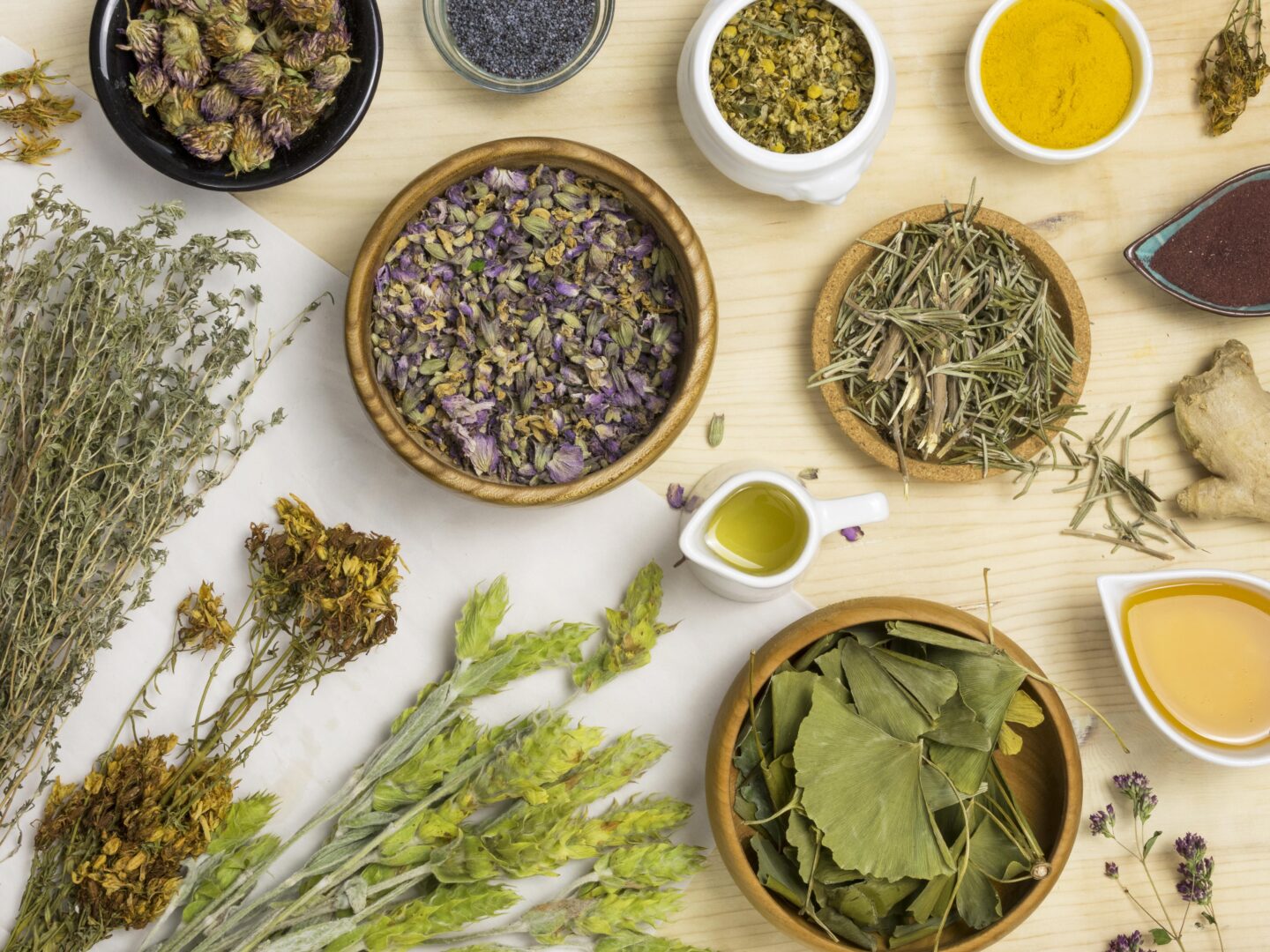 Ervas secas, flores e óleos naturais sobre a mesa, representando a prática da fitoterapia personalizada.