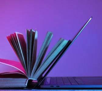 Livro aberto apoiado em um laptop, simbolizando a integração entre educação tradicional e tecnologia.