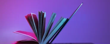 Livro aberto apoiado em um laptop, simbolizando a integração entre educação tradicional e tecnologia.