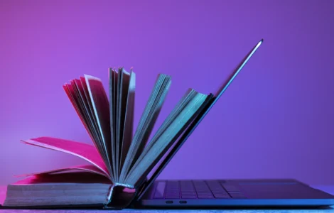 Livro aberto apoiado em um laptop, simbolizando a integração entre educação tradicional e tecnologia.