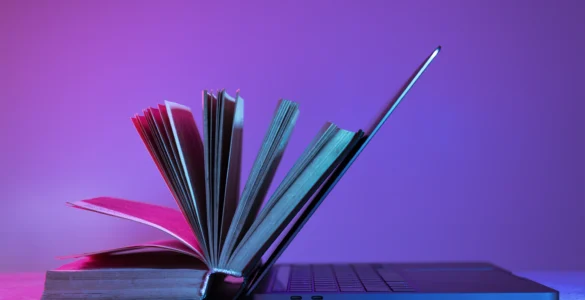 Livro aberto apoiado em um laptop, simbolizando a integração entre educação tradicional e tecnologia.