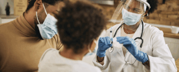 Profissional de saúde administrando vacina em paciente com máscara na clínica, destacando cuidados contra doenças.