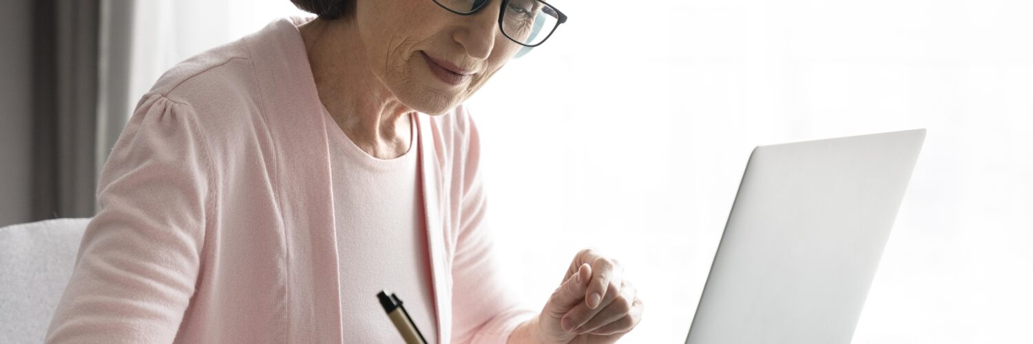 Mulher madura em casa, de fone de ouvido, estudando online. Ilustra as mudanças no EAD e o aprendizado remoto.