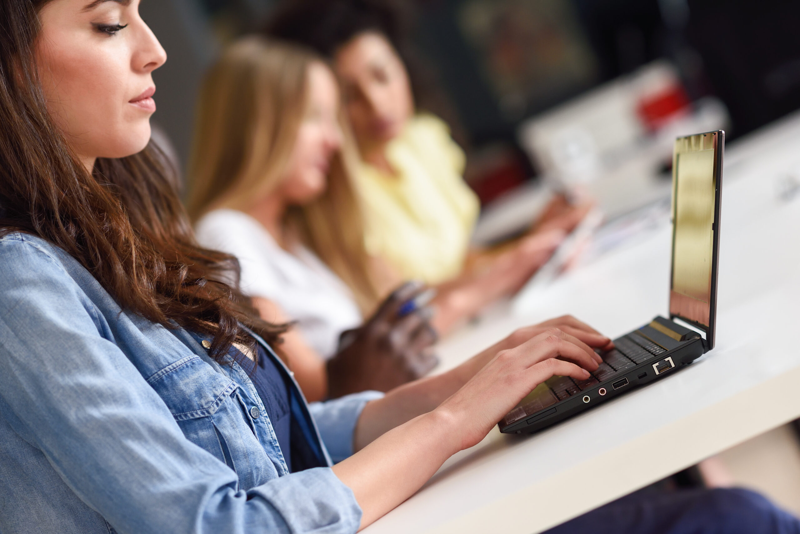 Young woman studying with laptop computer on white desk.