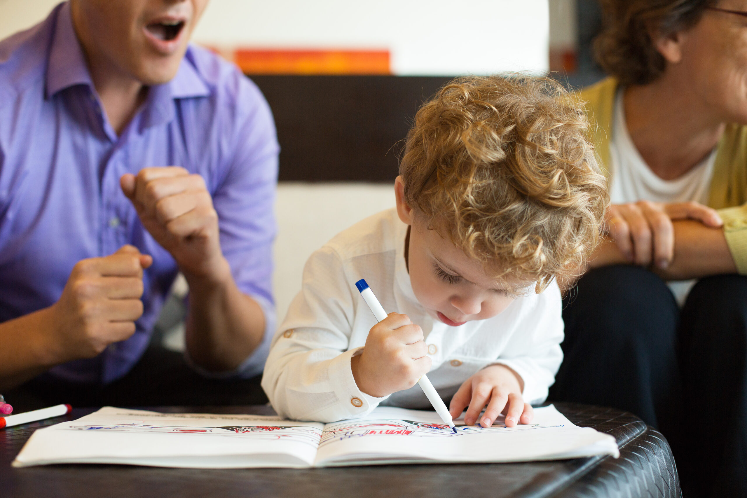 Dad, Granny and Cute Little Boy Drawing in Album