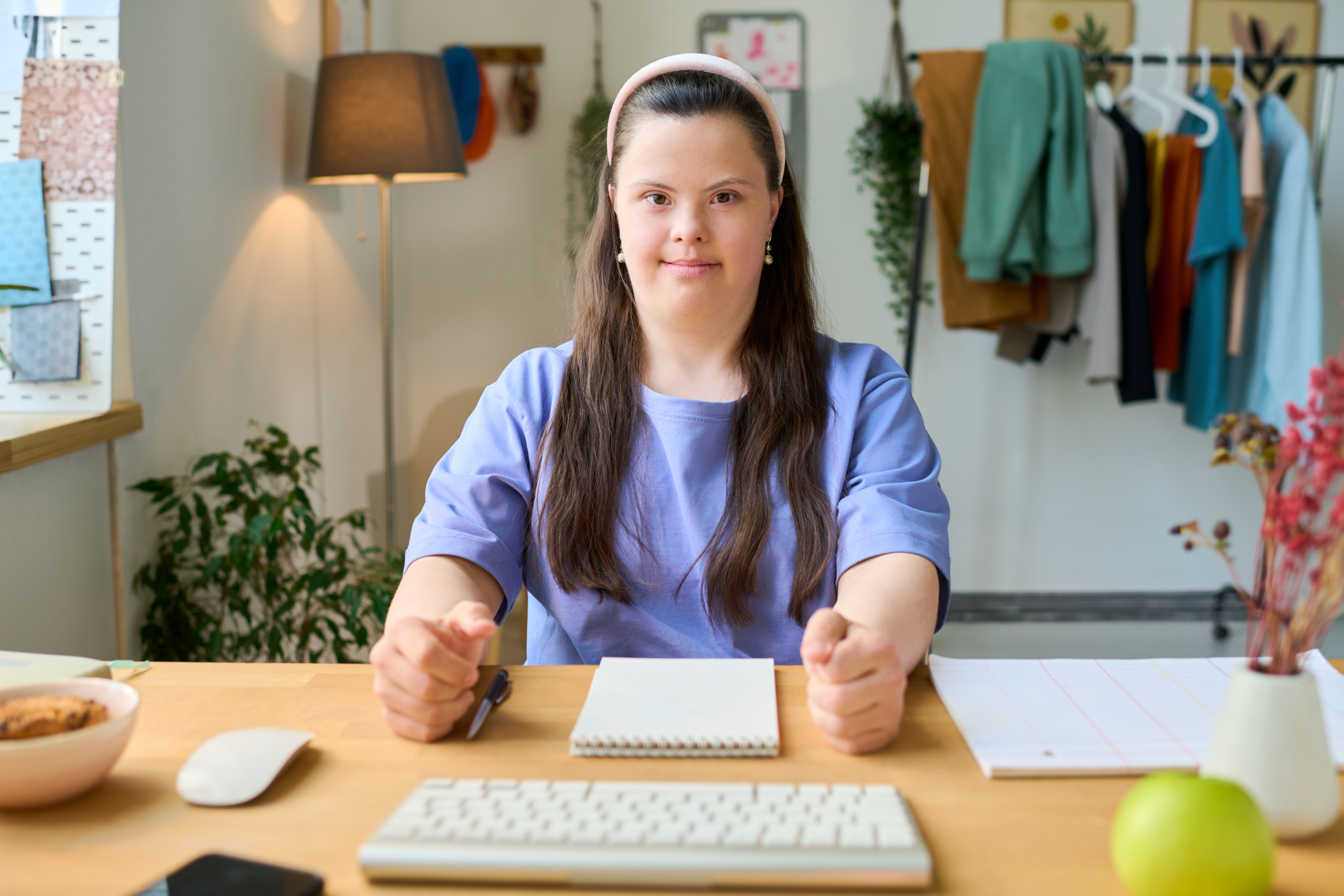 Happy young female with Down syndrome sitting by desk in front of computer