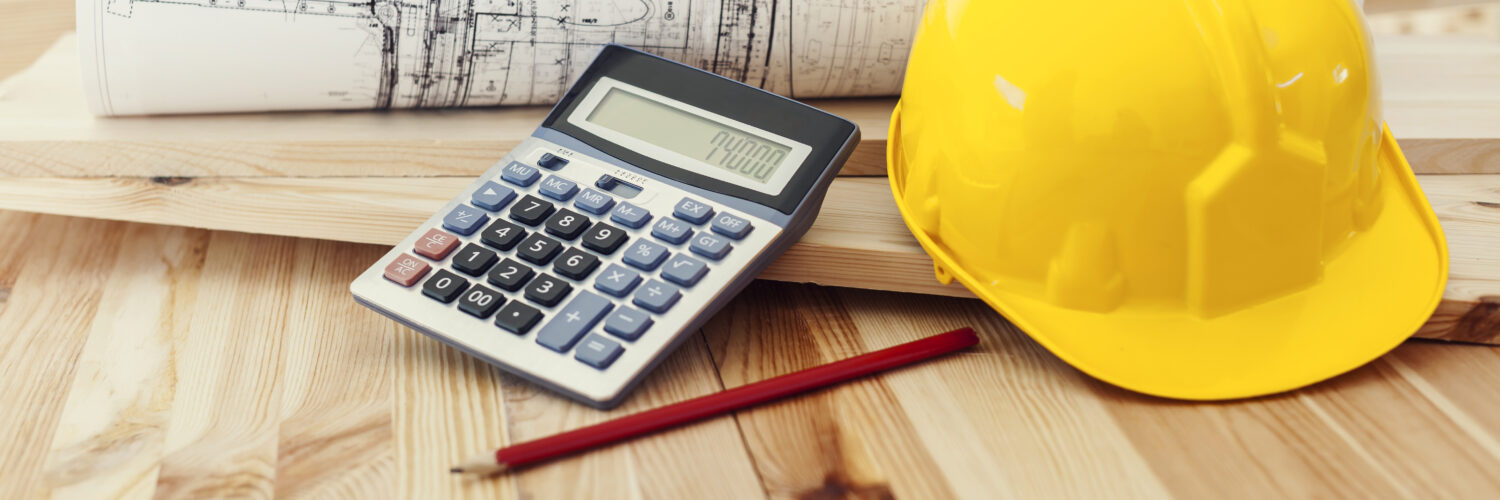 Yellow helmet with blueprints and calculator on wood