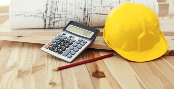 Yellow helmet with blueprints and calculator on wood