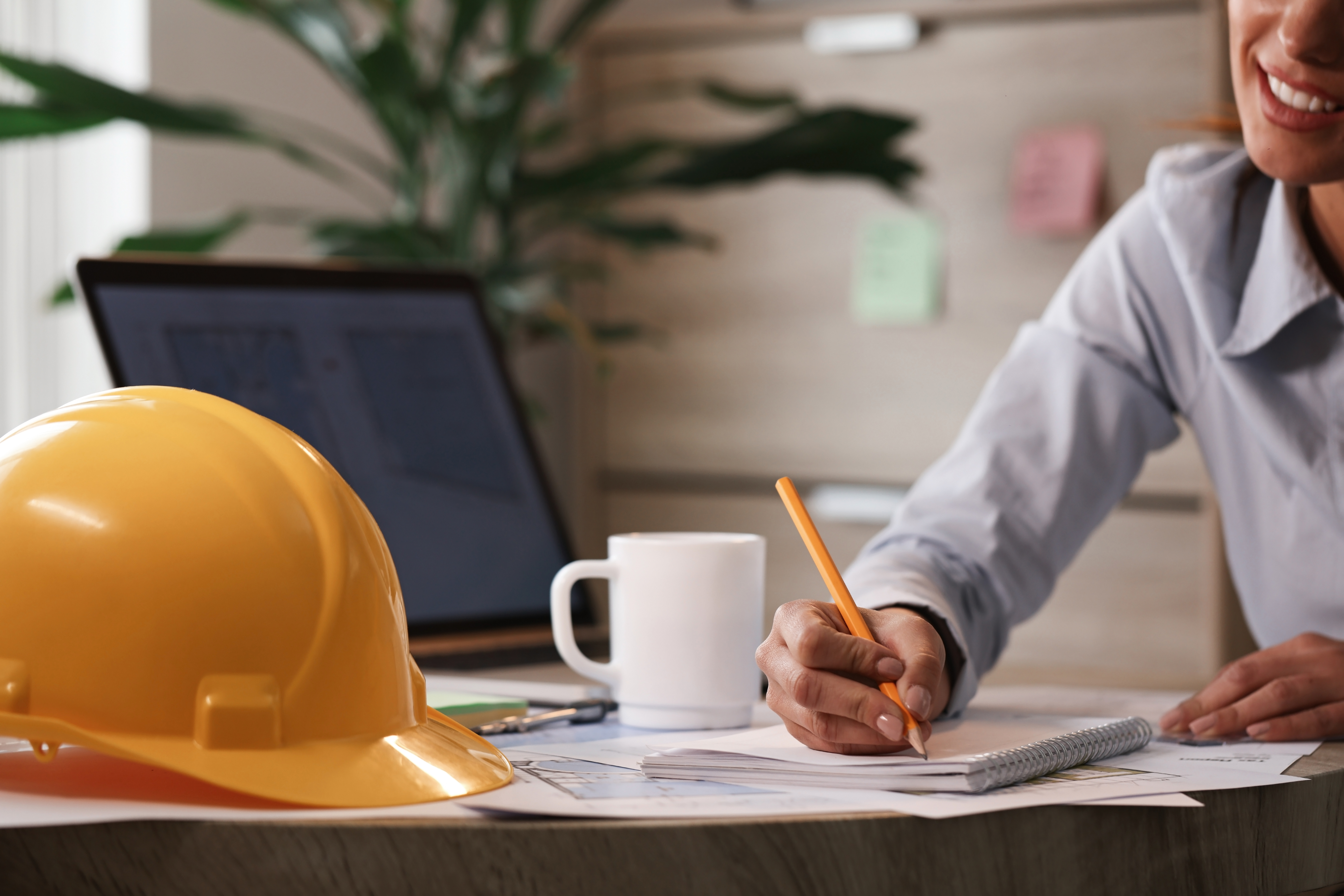 Female architect taking notes while working on new plans in the office.
