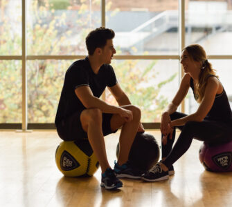 Man and Woman sitting with fitballs in the gym.