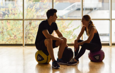 Man and Woman sitting with fitballs in the gym.